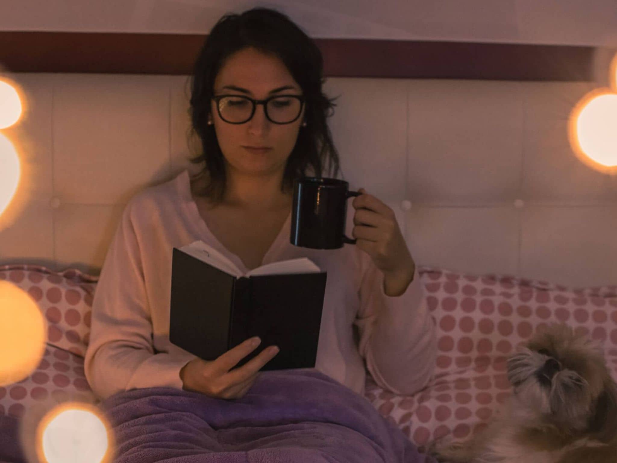 Erholsamer Schlaf: Frau sitzt am Abend auf dem Bett und liest.