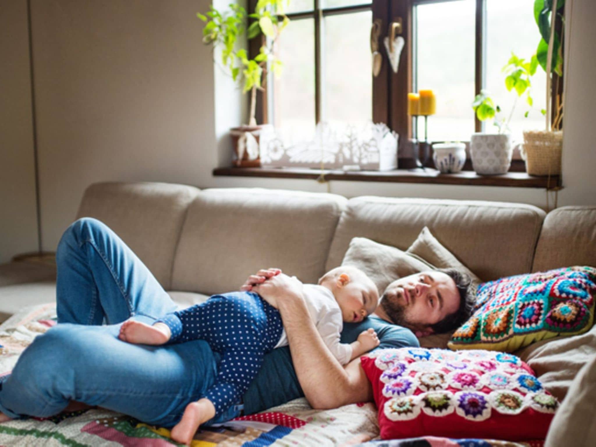Mittagsschlaf: Vater mit einem kleinen Mädchen zu Hause, das auf dem Sofa schläft.