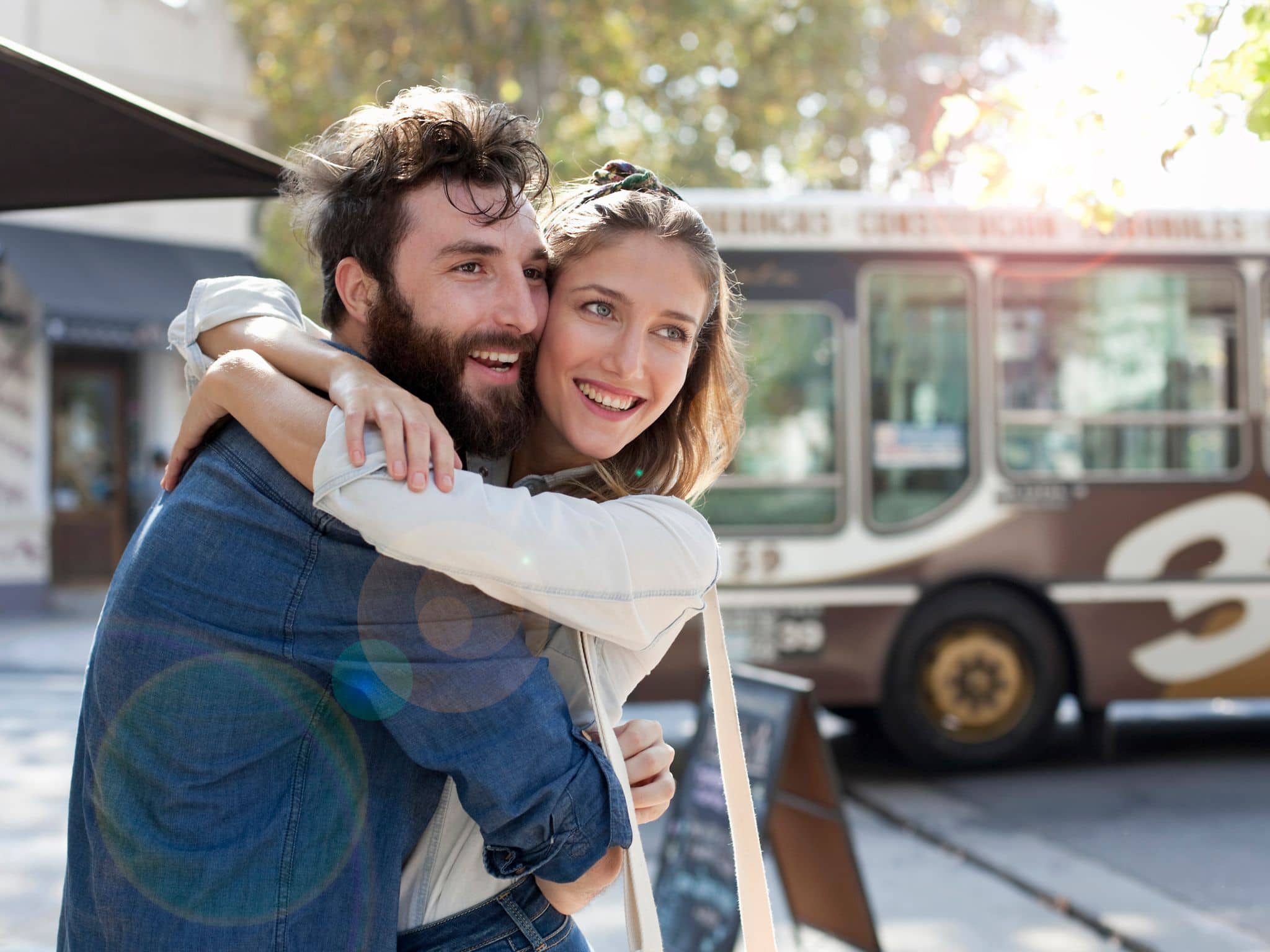 Symbolbild Vorhaut: Ein junge Mann nimmt eine junge Frau von hinten in den Arm und lächelt