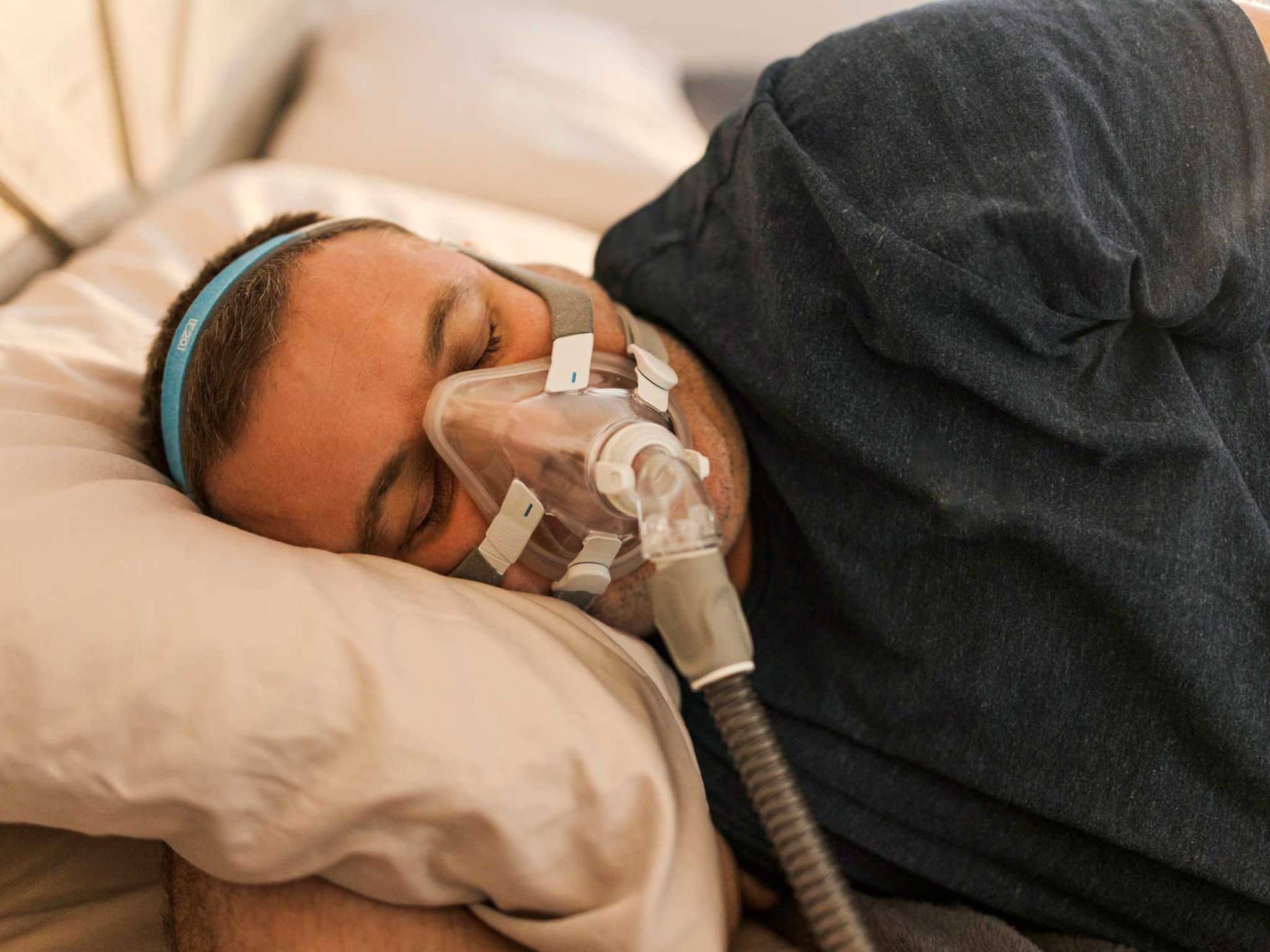 Mann schläft mit CPAP-Gerät