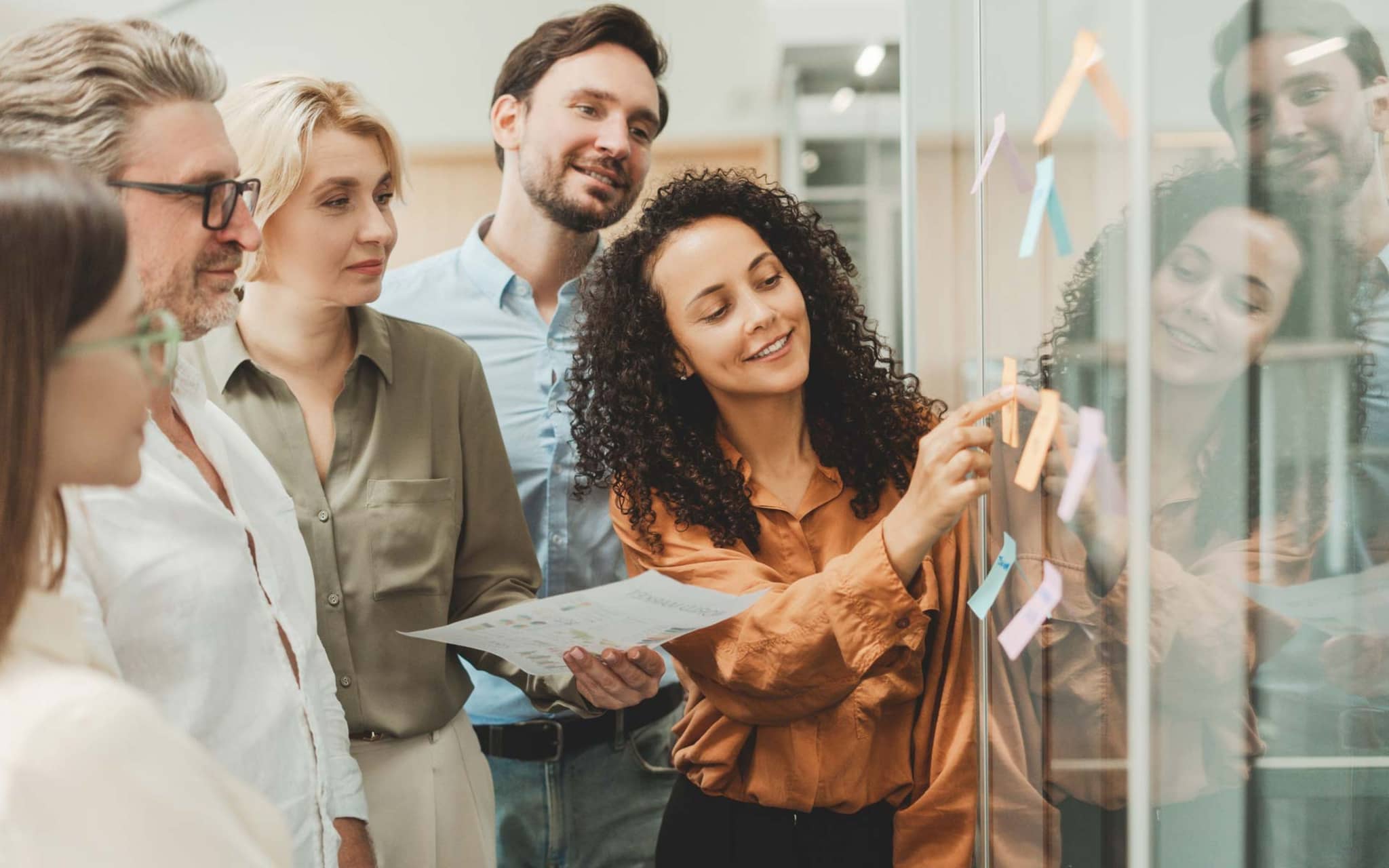 Gesundheitsreport 2025: Gruppe von jungen Leuten klebt bei einem Workshop im Büro Post-its an eine Glaswand.