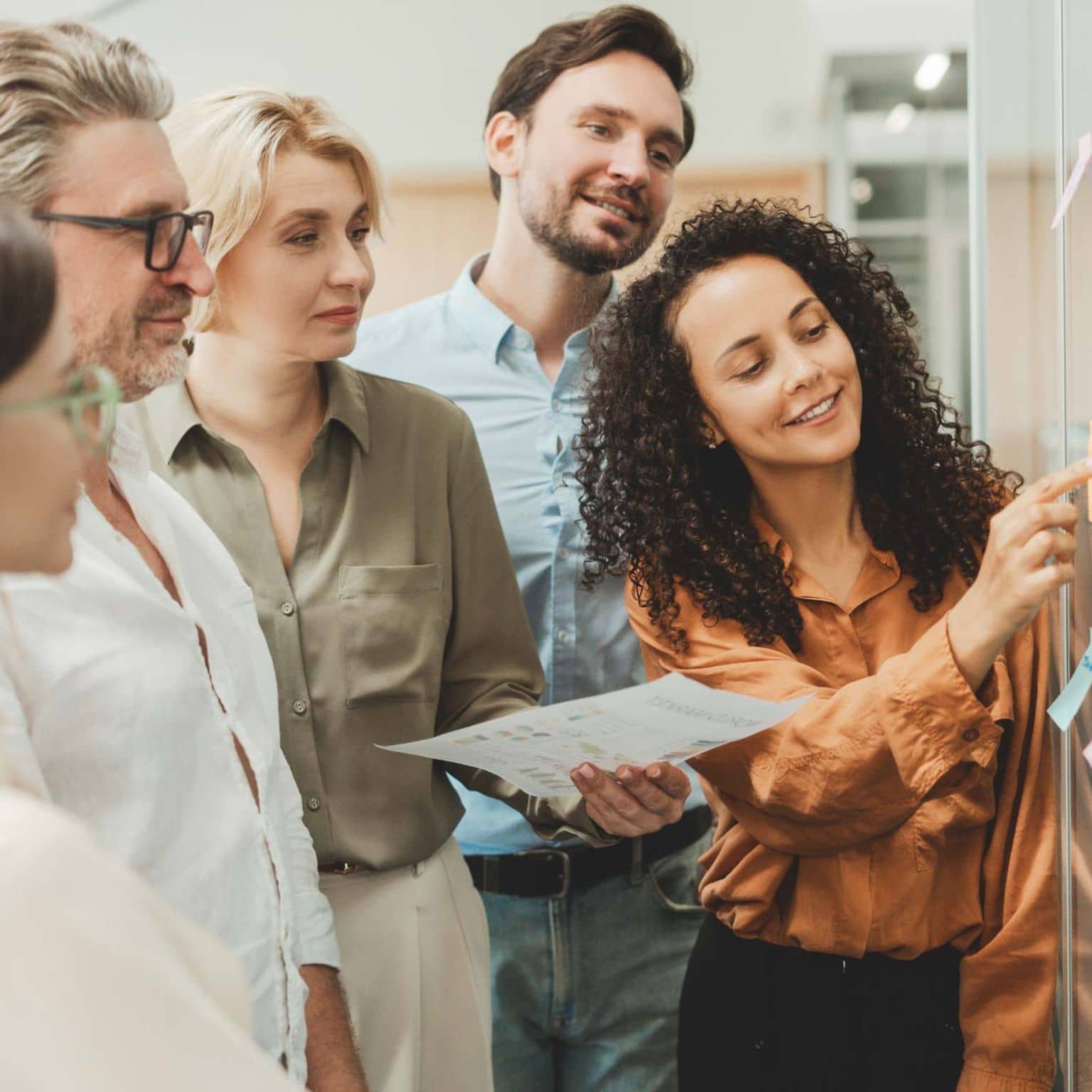 Gesundheitsreport 2025: Gruppe von jungen Leuten klebt bei einem Workshop im Büro Post-its an eine Glaswand.