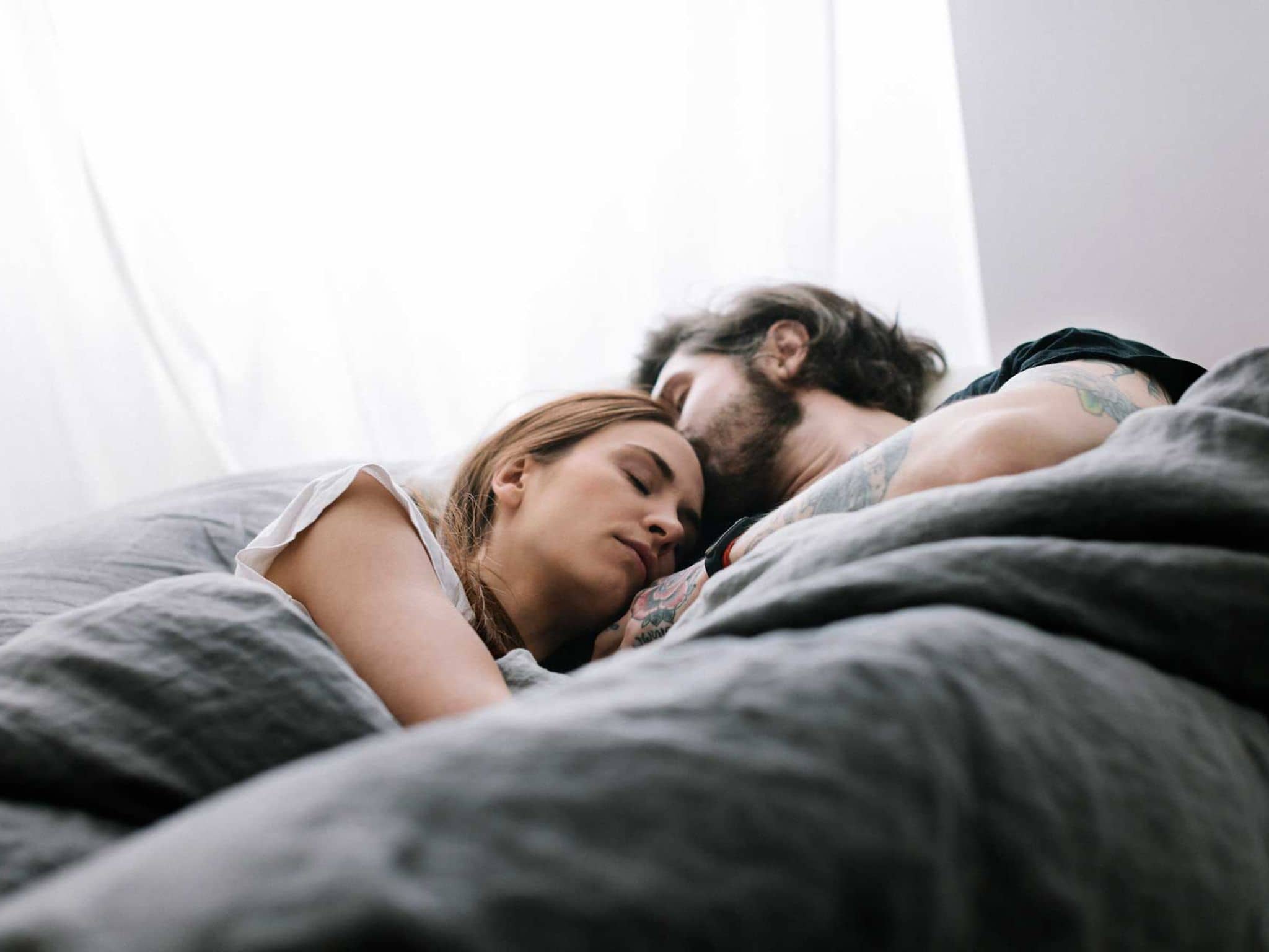 Junges Paar kuschelt verschlafen im Bett