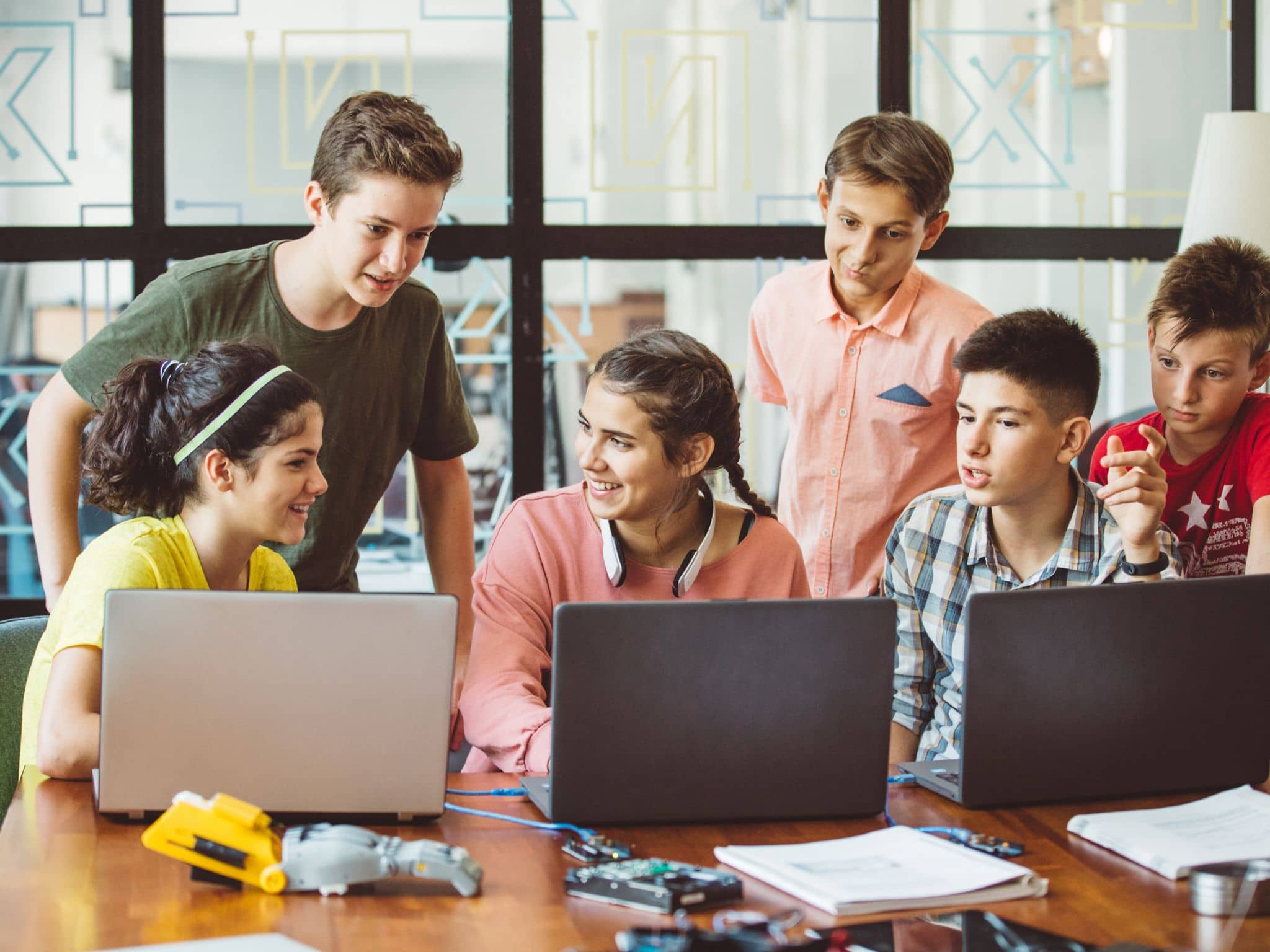 Bild: Eine Gruppe von Jugendlichen sitzt um Computer herum und lernt.