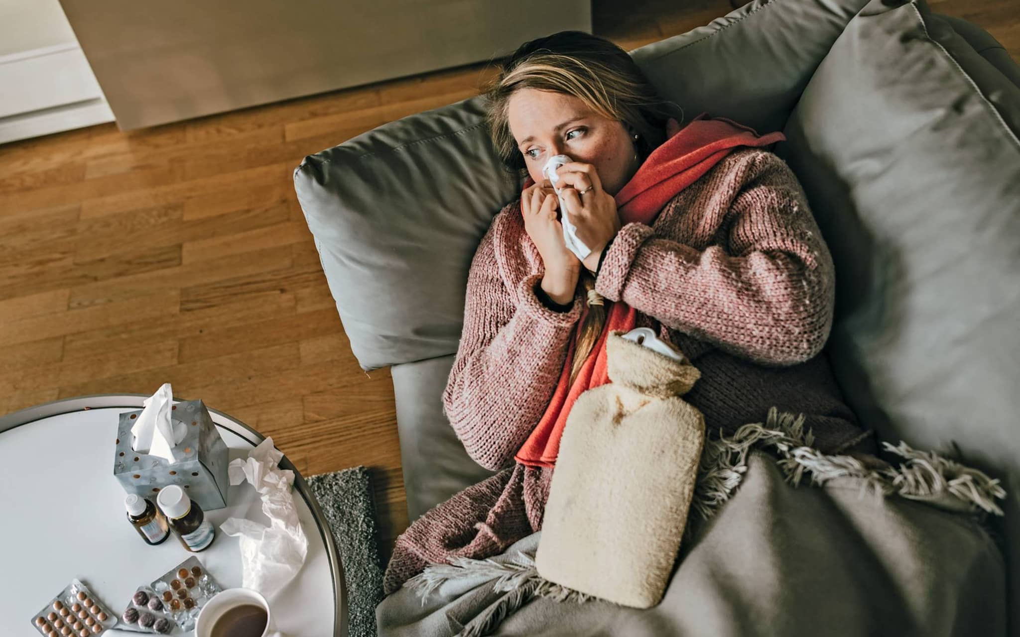 Eine Frau mit Erkältung oder Grippe liegt auf dem Sofa um sich zu erholen.