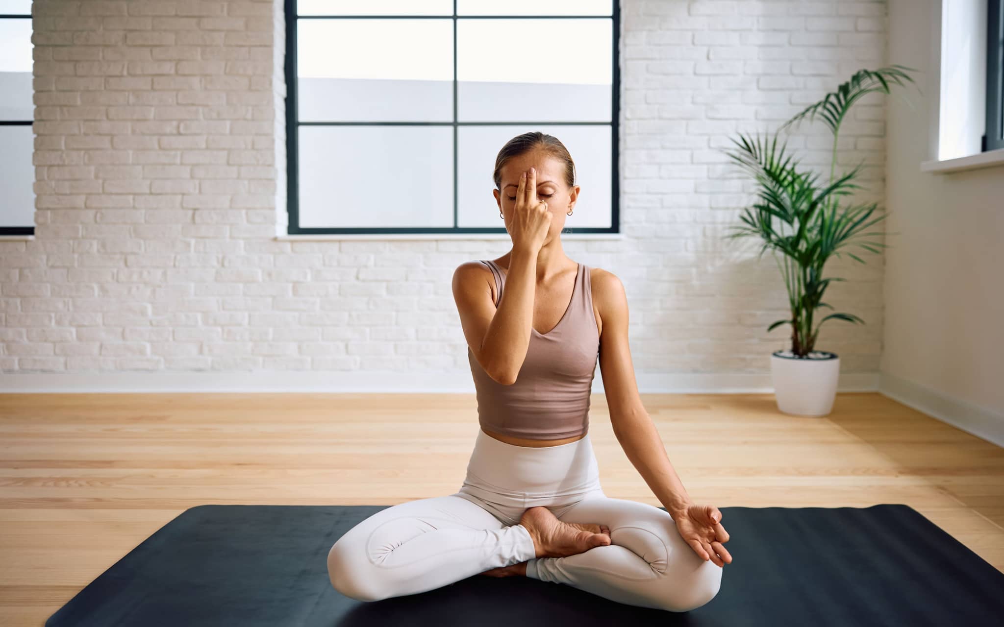 Pranayama: Eine Frau sitzt im Schneidersitz und praktiziert die Wechselatmung