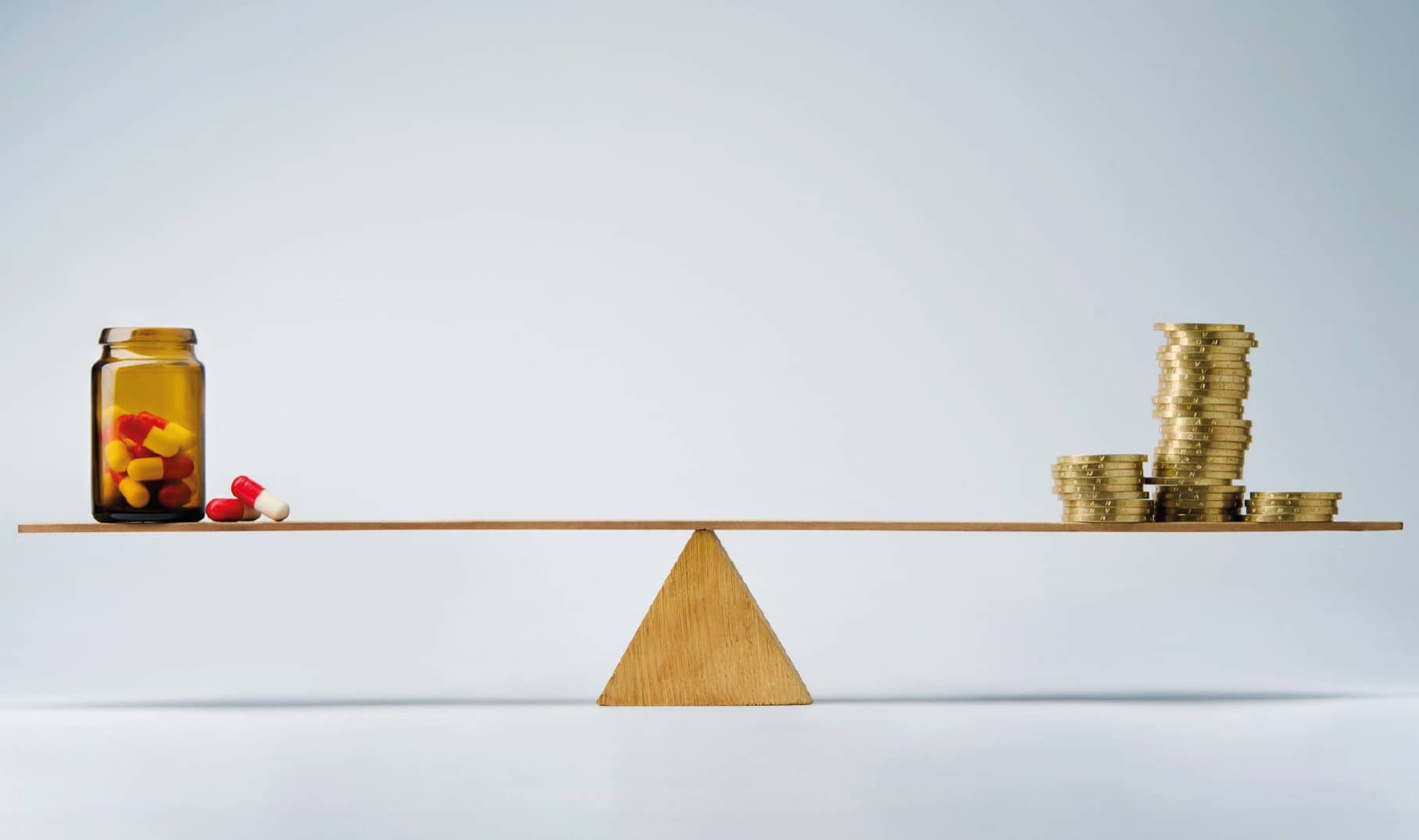 Ein Glas mit Medikamenten und ein Stapel Münzen