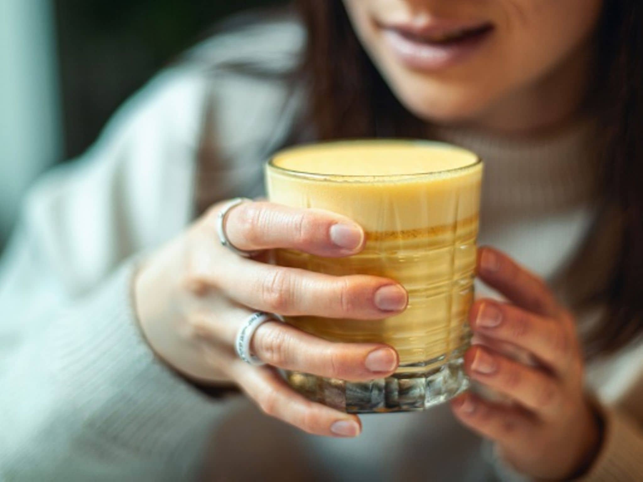 Eine Frau hält ein Glas goldene Milch in der Hand