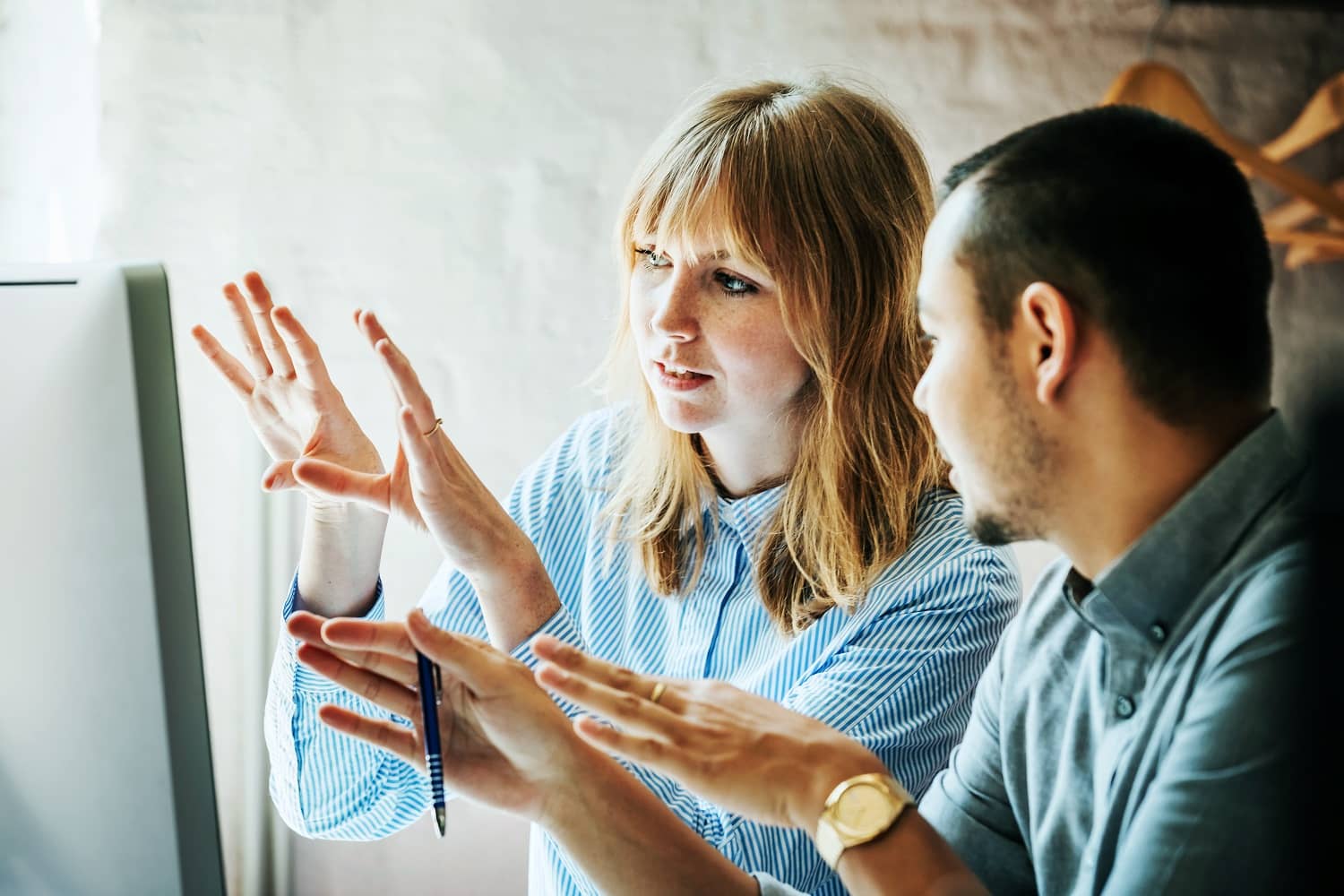 Eine Frau und ein Mann diskutieren etwas am Computer.