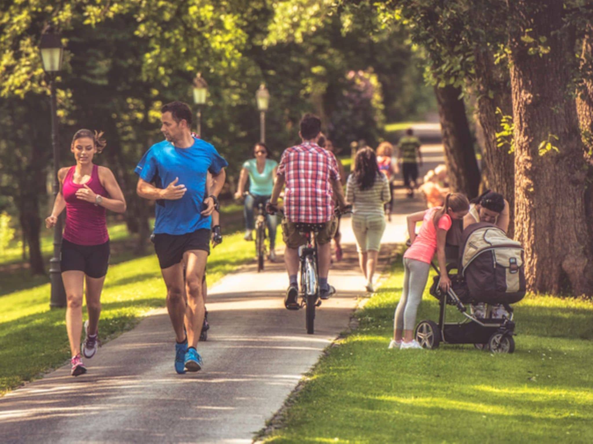 Sport und Gesundheit: Paar joggt an einem sonnigen Tag durch einen belebten Park.