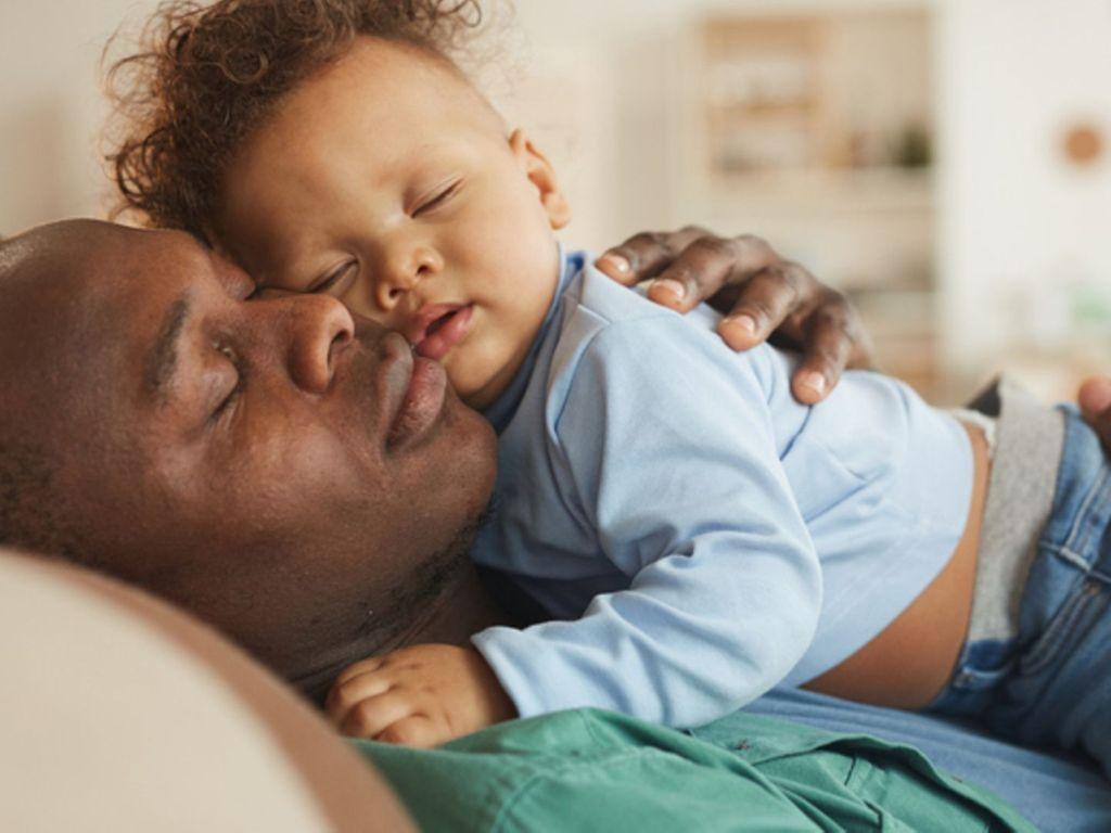 Babyschlaf: Vater schläft mit seinem Baby im Arm