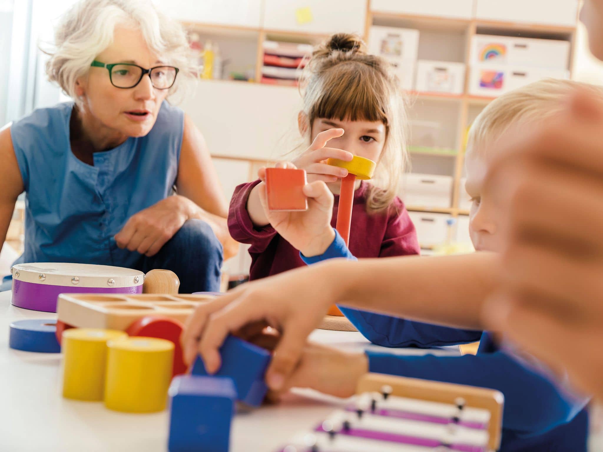 Ältere Frau arbeitet im Kindergarten mit Kindern.