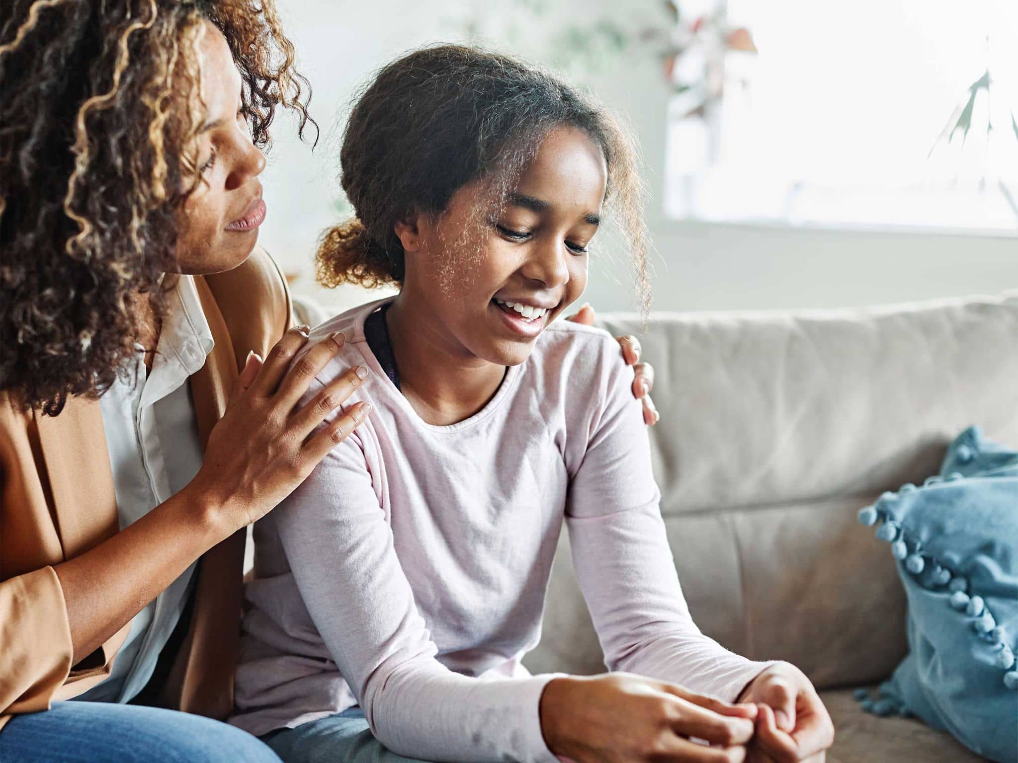 Mutter fasst ihrer Tochter liebevoll an die Schultern und hört ihr zu