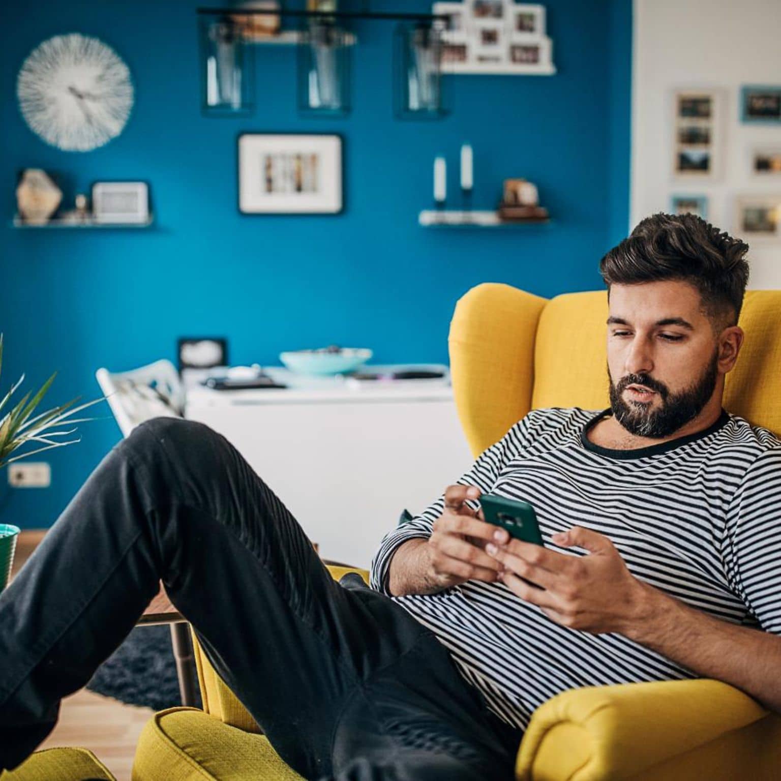 DAK App: Mann sitzt auf Sessel und nutzt entspannt sein Smartphone