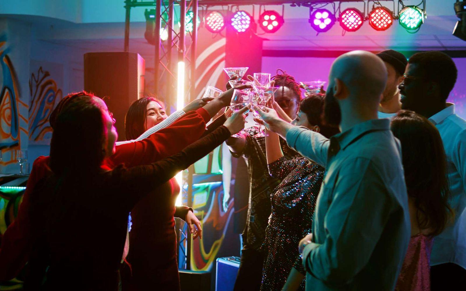 Party ohne Alkohol: Partygäste stoßen auf der Tanzfläche mit ihren alkoholfreien Drinks an.