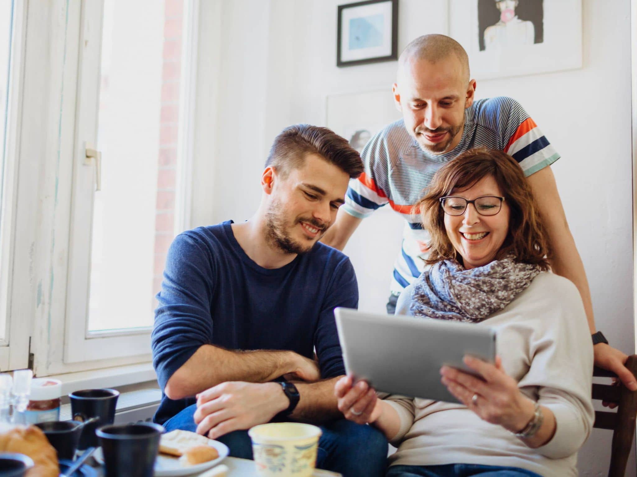Bild: Frau und zwei Männer schauen auf ein Tablet, auf dem die Selbstlernkurse sind.