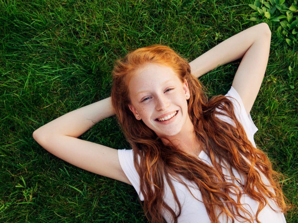 Symbolbild Busen-Wissen: Ein junges Mädchen liegt auf dem Rasen