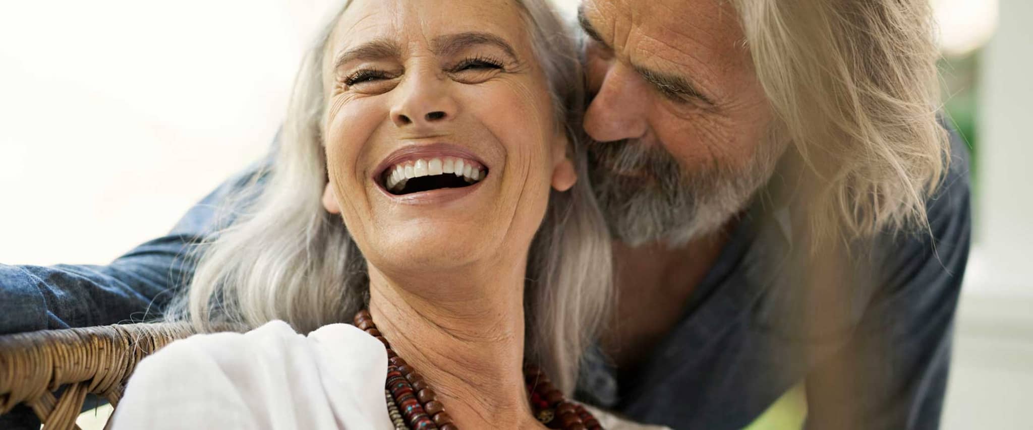 Glückliches Ehepaar lacht: Auch im Alter gut versichert