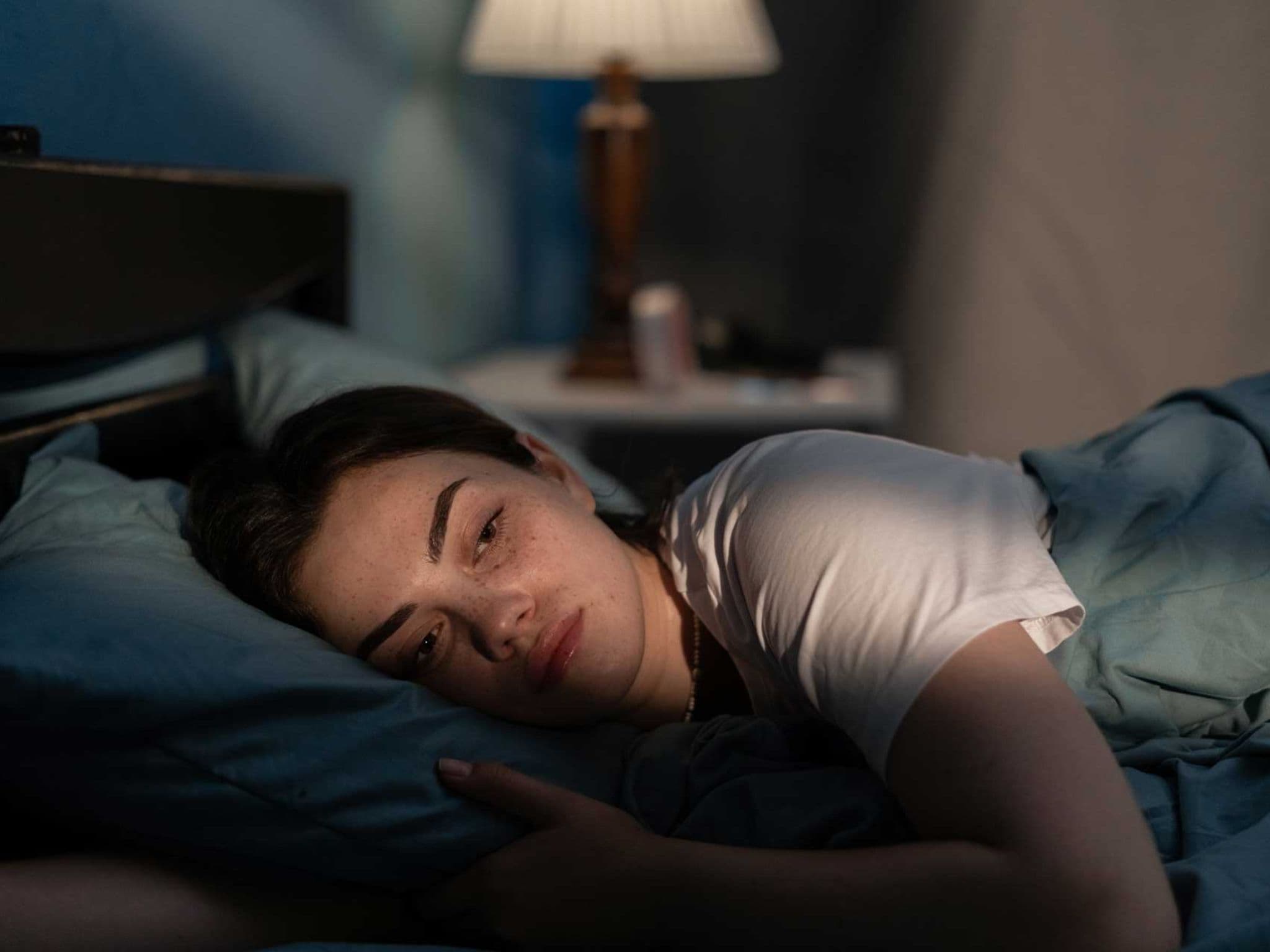 Symbolbild Schlafstörungen: Junge Frau liegt wach im Bett