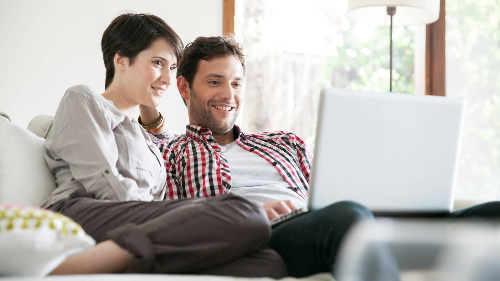 Qualitätstransparenzbericht 2025: Mann und Frau sitzen auf dem Sofa und schauen gemeinsam auf den Bildschirm eines Notebooks.