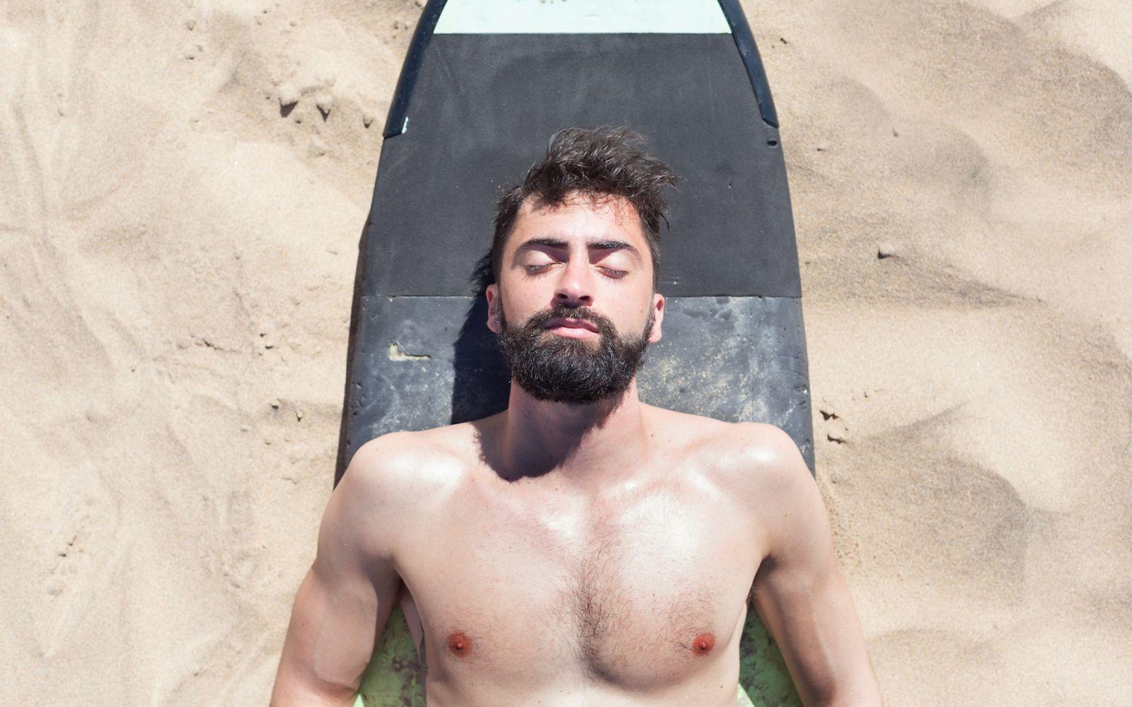 Hübscher Surfer entspannt sich am Strand