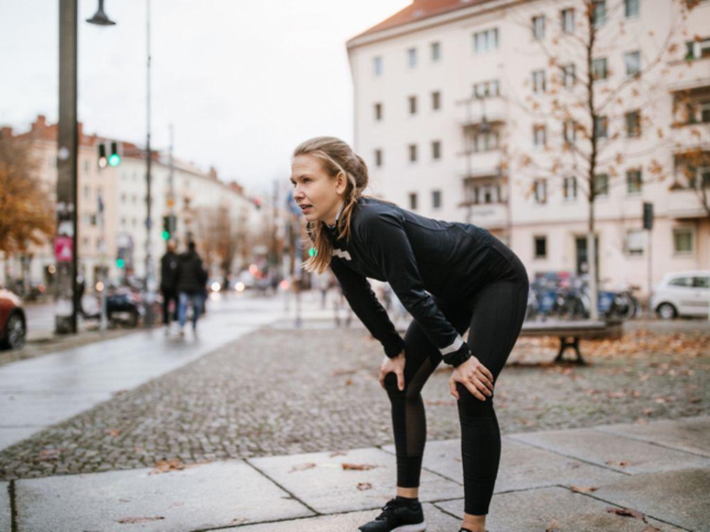 Athletin, die sich nach dem Training entspannt und ihre Hände auf die Knie legt.