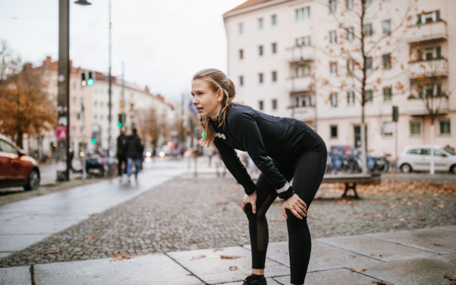 Athletin, die sich nach dem Training entspannt und ihre Hände auf die Knie legt.