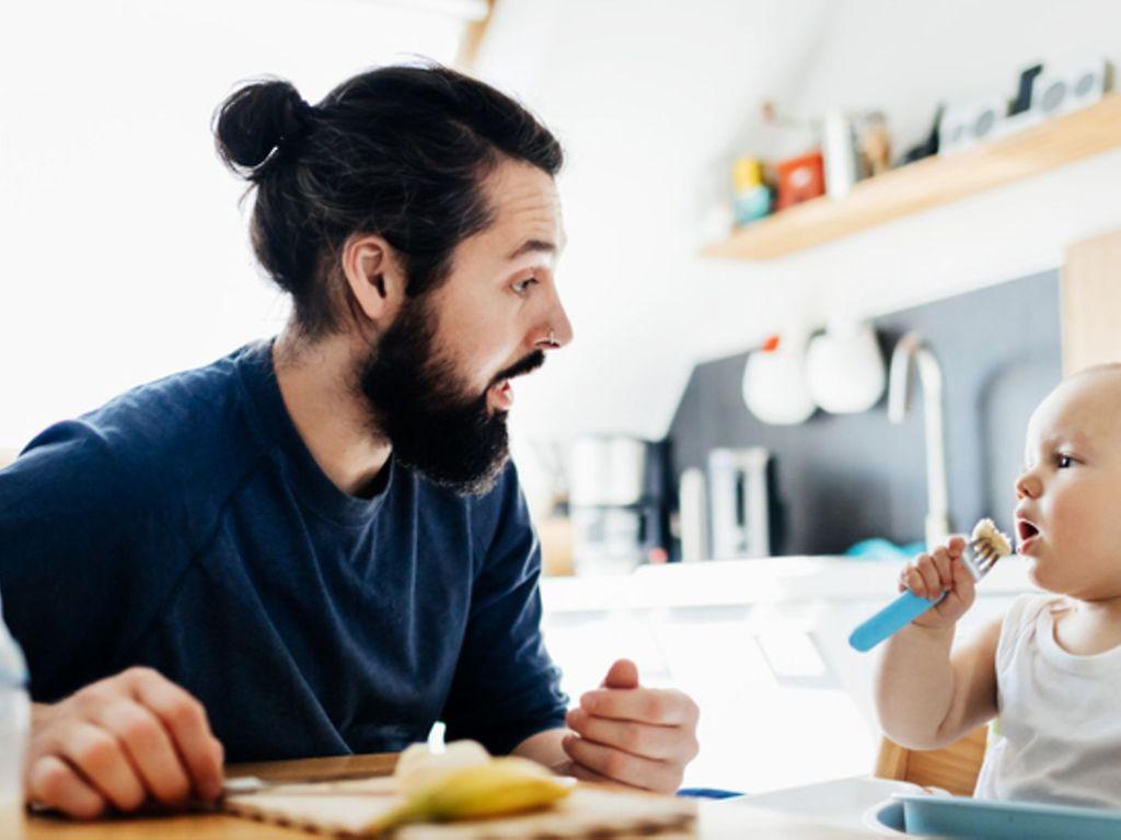 Kinder gesund ernähren: Ein Vater bereitet seinem kleinen Kind eine Banane zum Essen vor.