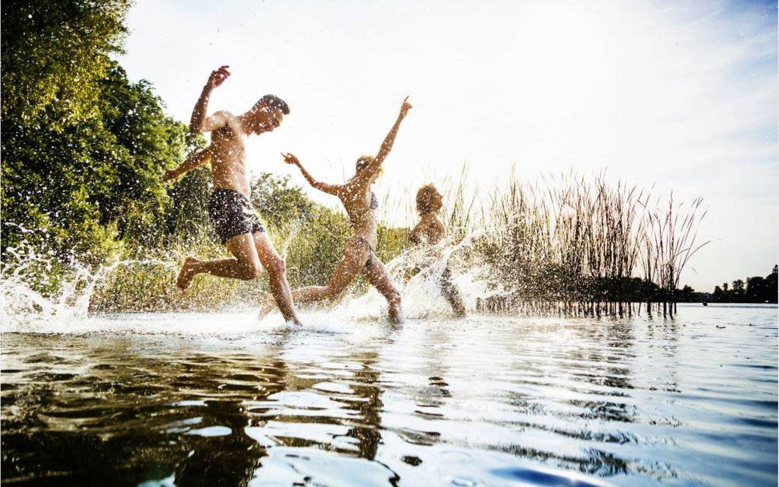 Movement Culture: Eine Gruppe von Freunden, die an einem gemeinsamen Tag am See aufgeregt im Wasser planscht.