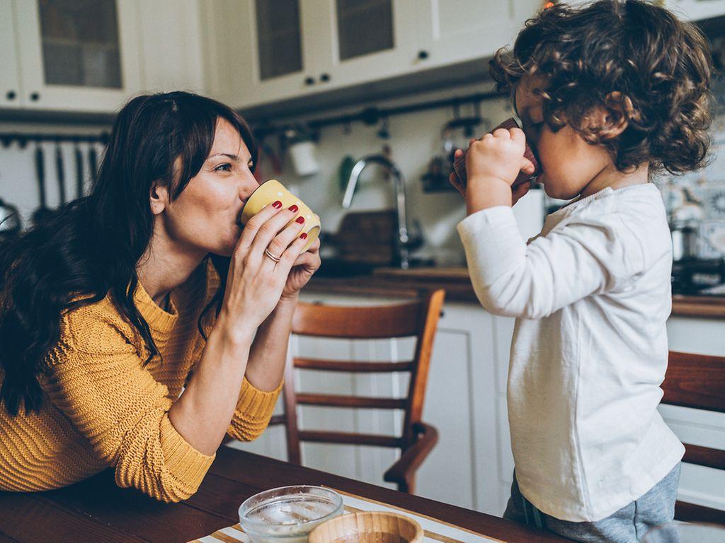 Entschleunigung: Mutter und Sohn spielen in der Küche und trinken Tee.