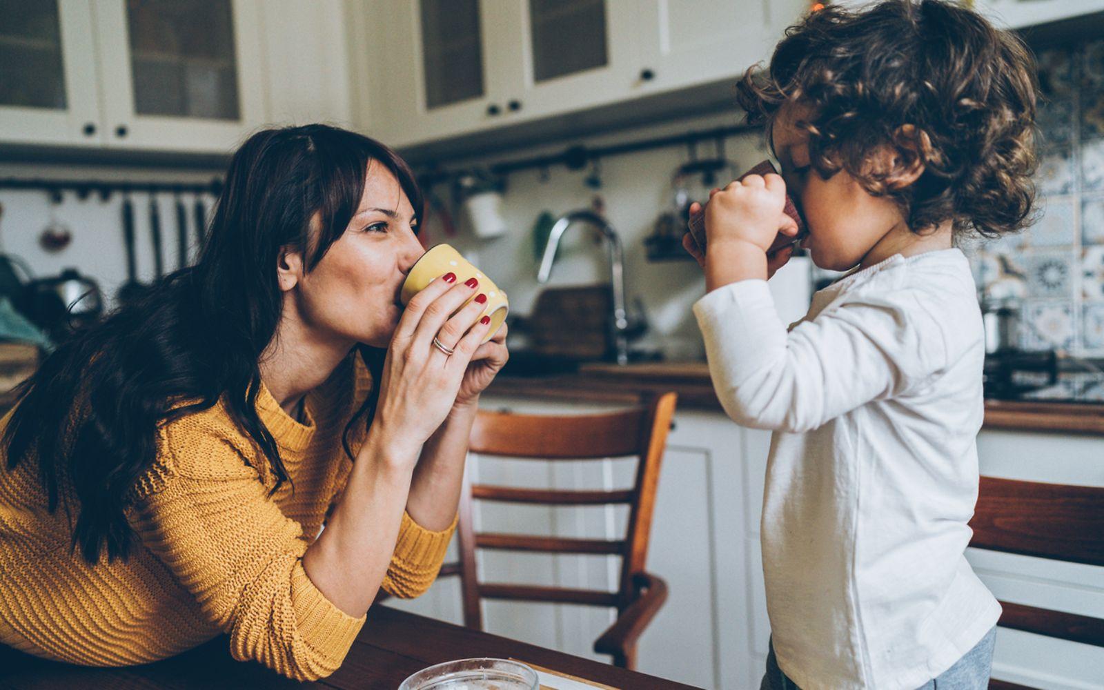 Entschleunigung: Mutter und Sohn spielen in der Küche und trinken Tee.