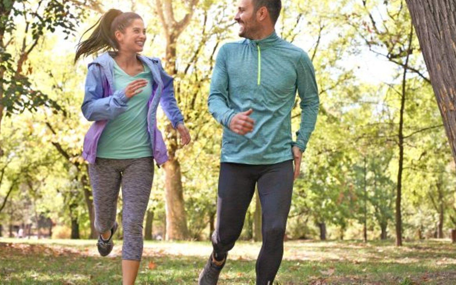 Fit im Frühling: Ein Mann und eine Frau joggen durch den Wald.