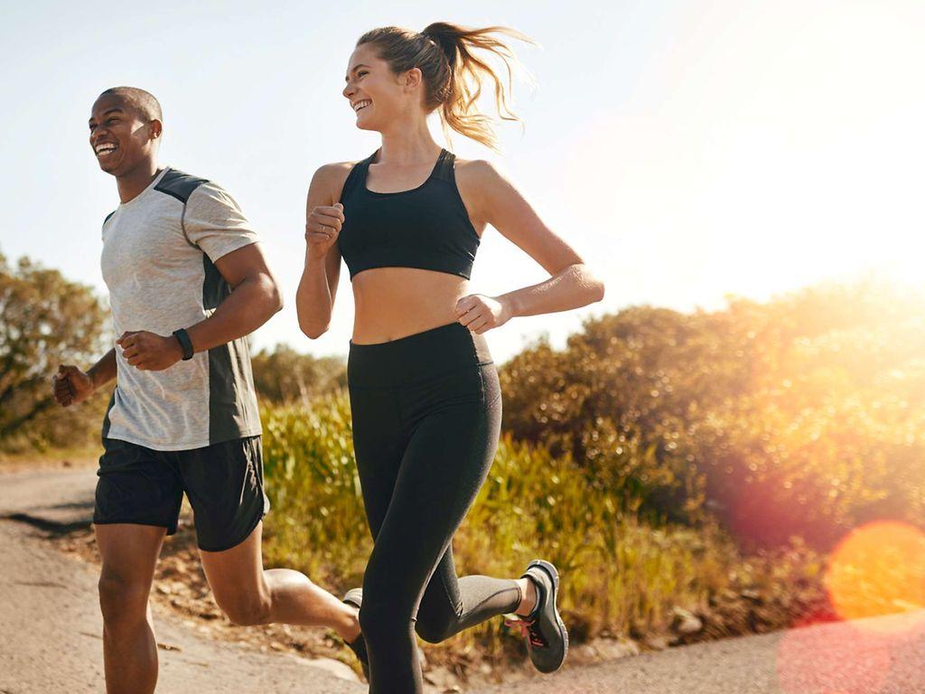 Marathon: Eine Frau und ein Mann joggen gemeinsam durch die Natur.