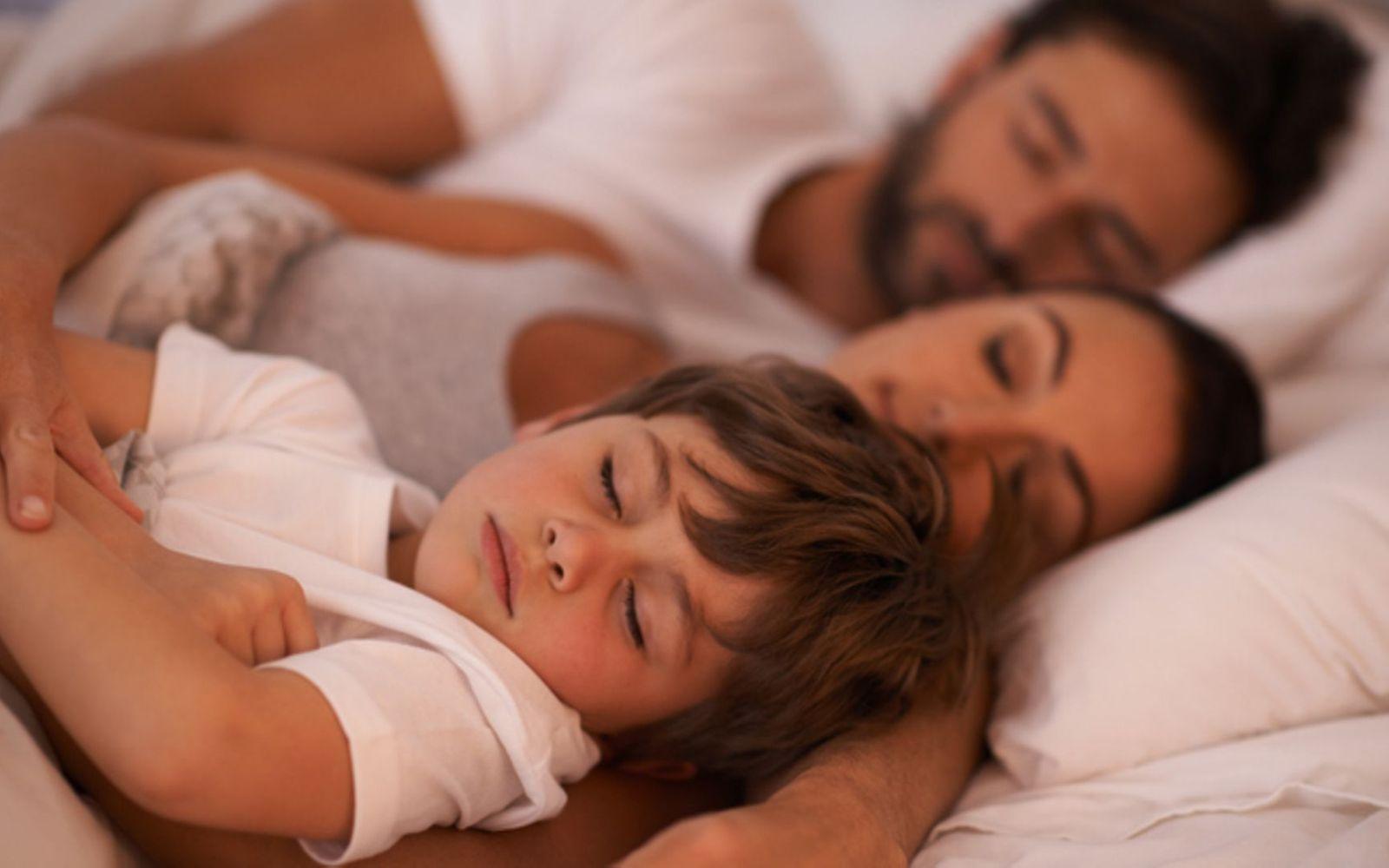 Symbolbild für Co-Sleeping: Ein Kind schläft mit im Bett seiner Eltern