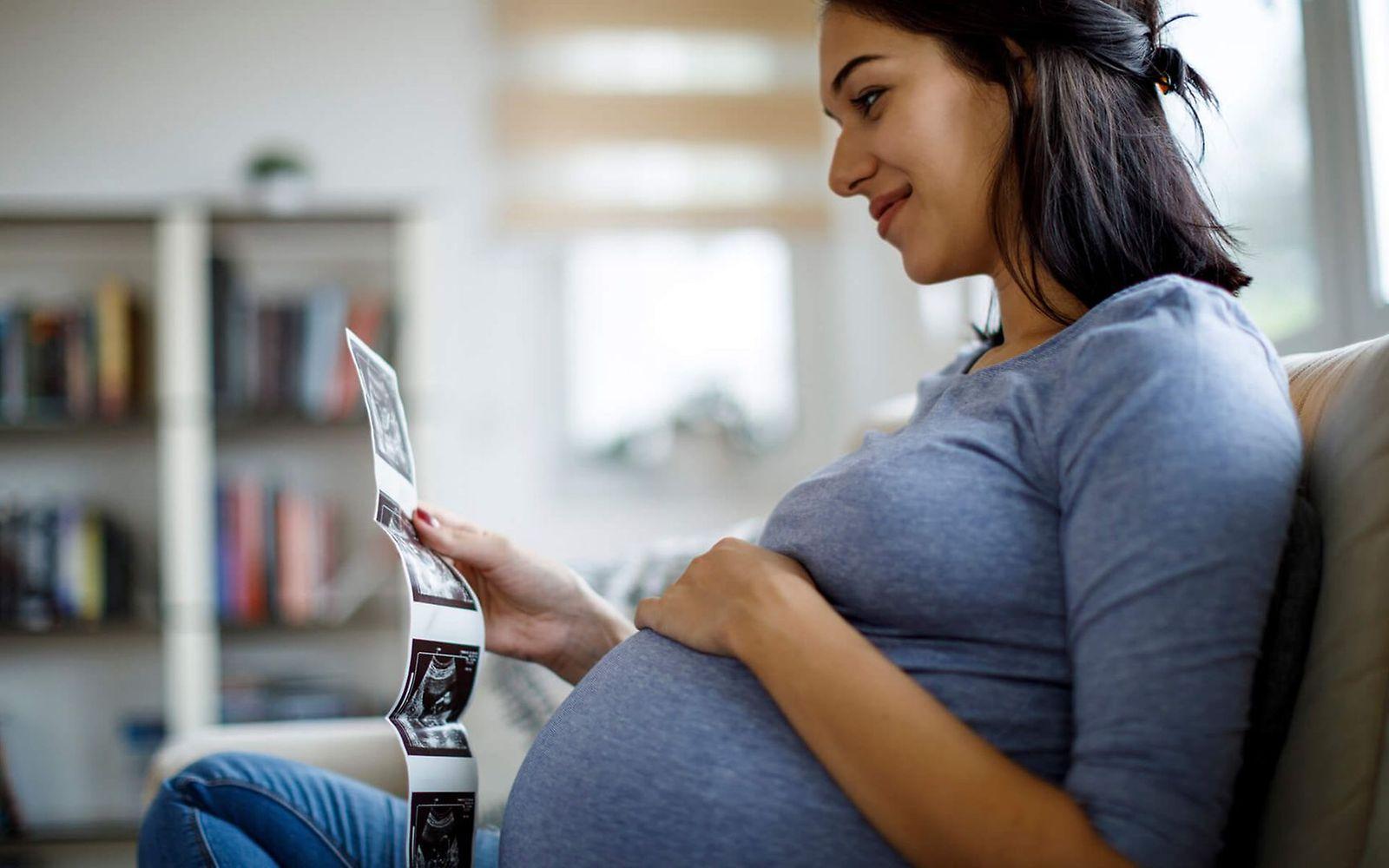 Glückliche schwangere Frau, die Ultraschall-Scan zu Hause