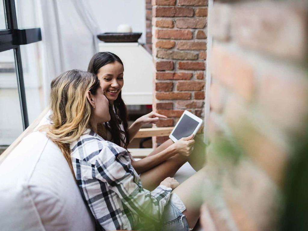 J1 Untersuchung: Zwei Mädchen schauen lachend auf ein Tablet.