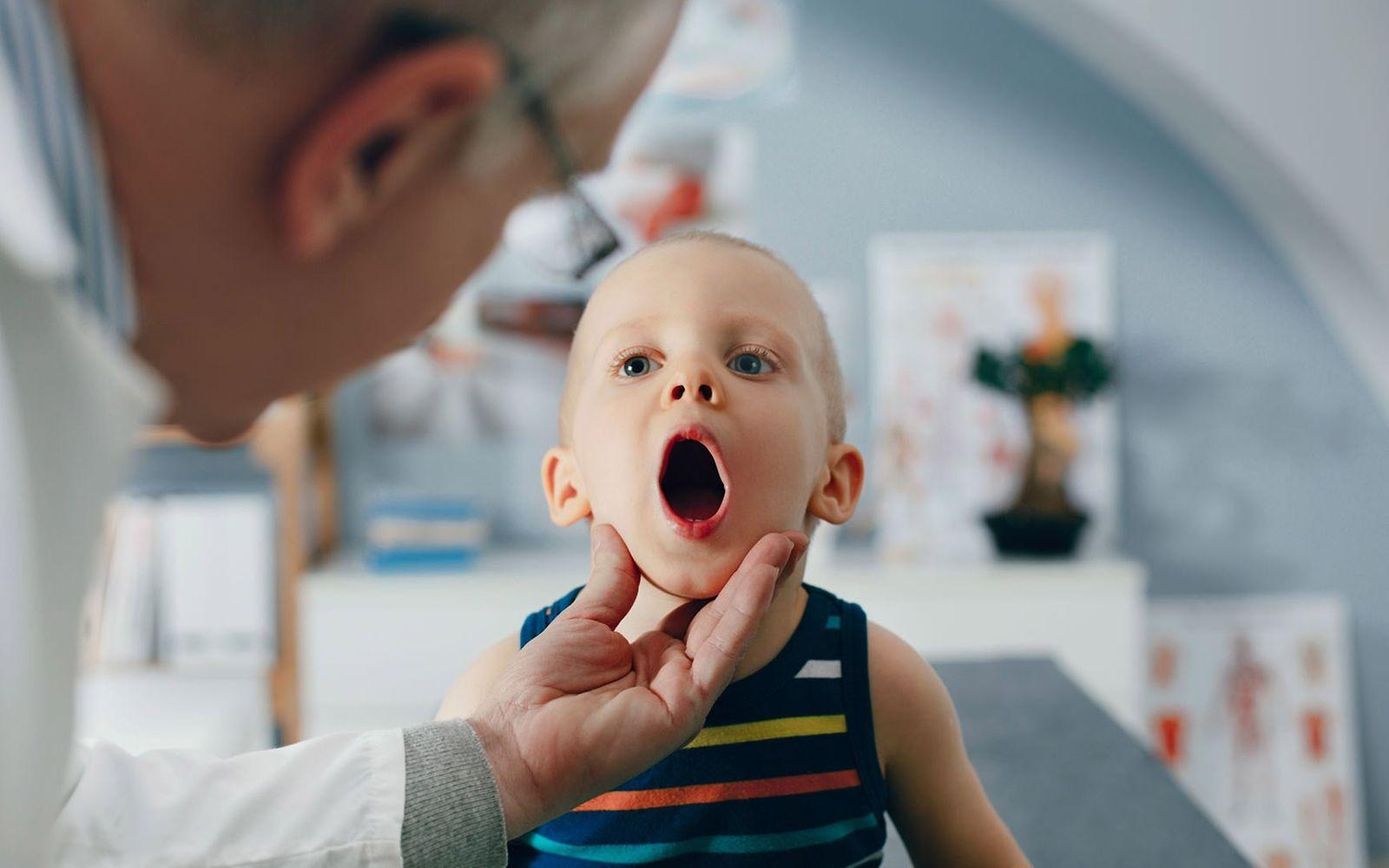 U8 Untersuchung: Arzt schaut einem kleinen Jungen in den Mund.