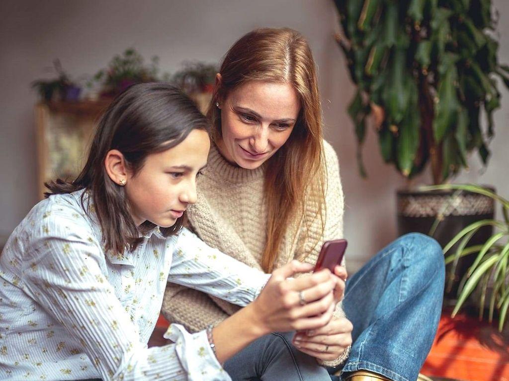 Bild: Tochter zeigt ihrer Mutter etwas auf dem Handy.