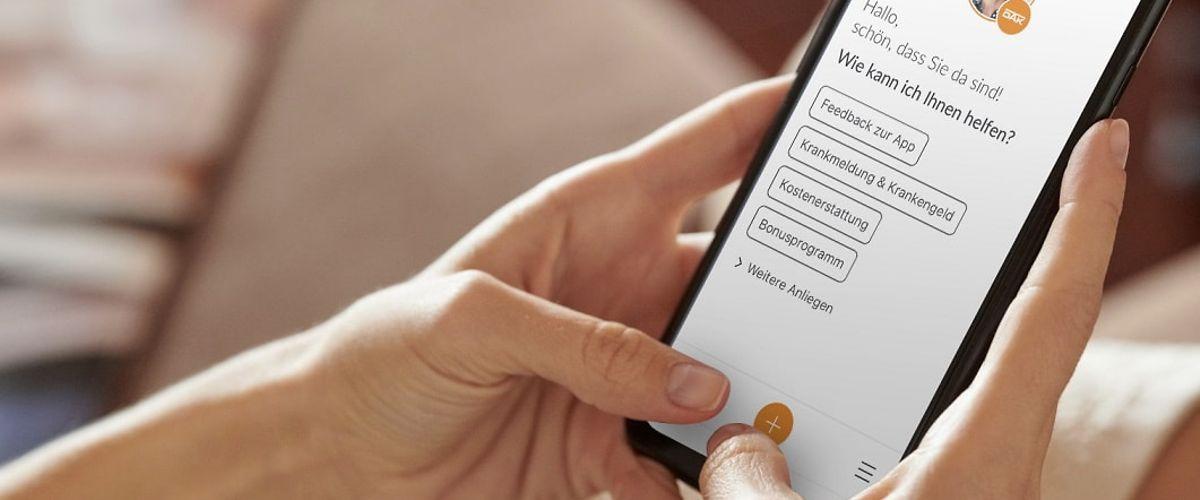Bild: Eine Frau bedient an einem Handy die DAK App.