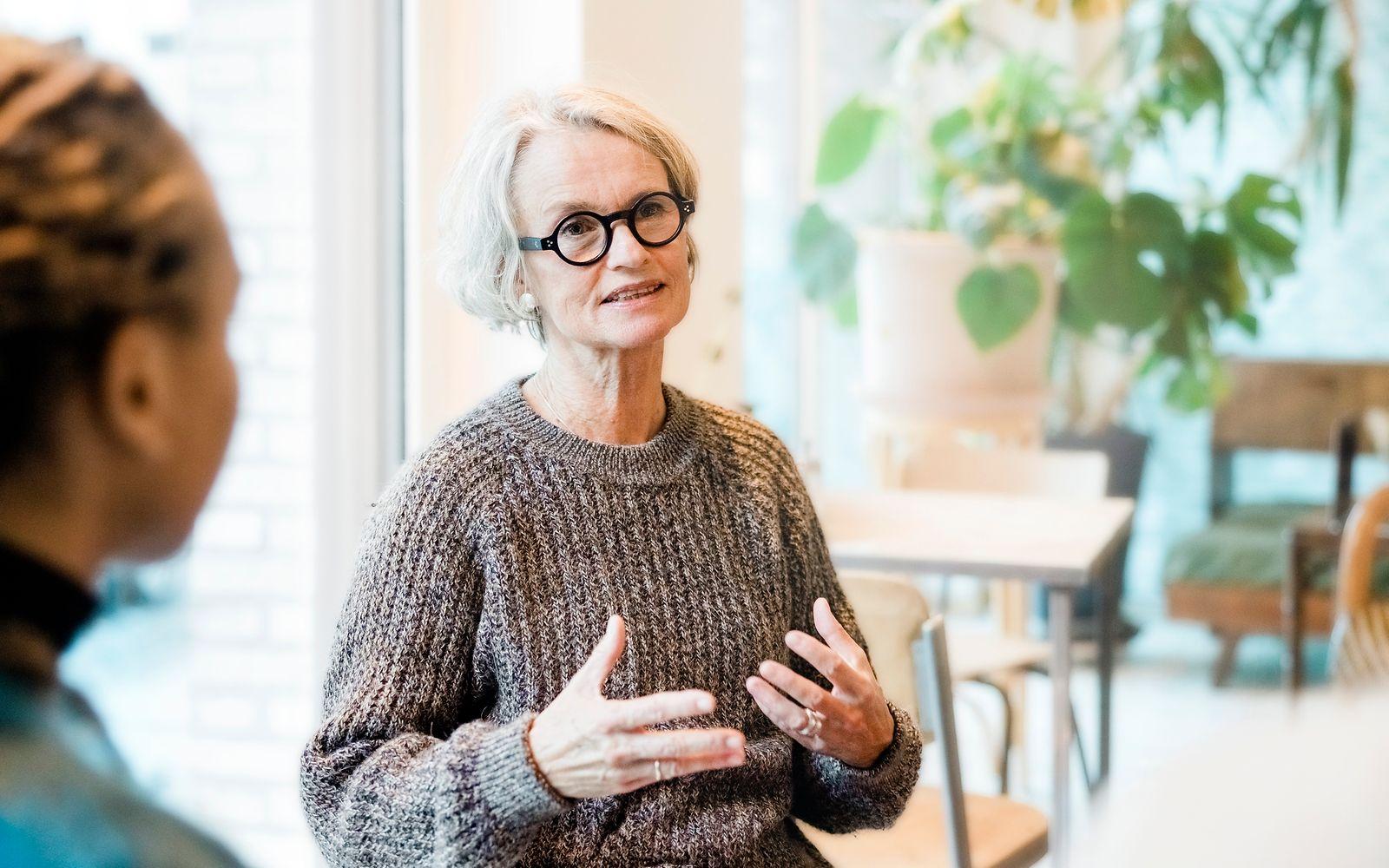 Bild: Frau mit weißen Haaren und Brille spricht während einer Gruppentherapie.