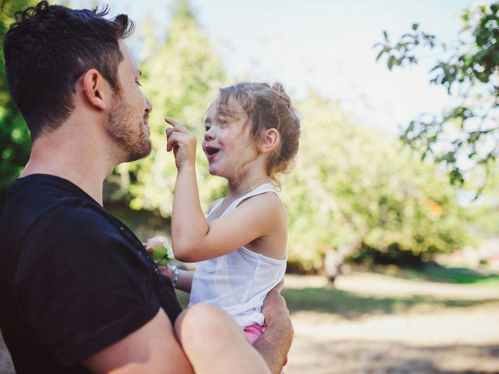 AktivBonus Junior: Vater mit Tochter auf dem Arm im Freien.