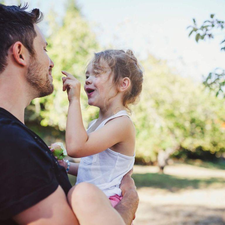 AktivBonus Junior: Vater mit Tochter auf dem Arm im Freien.