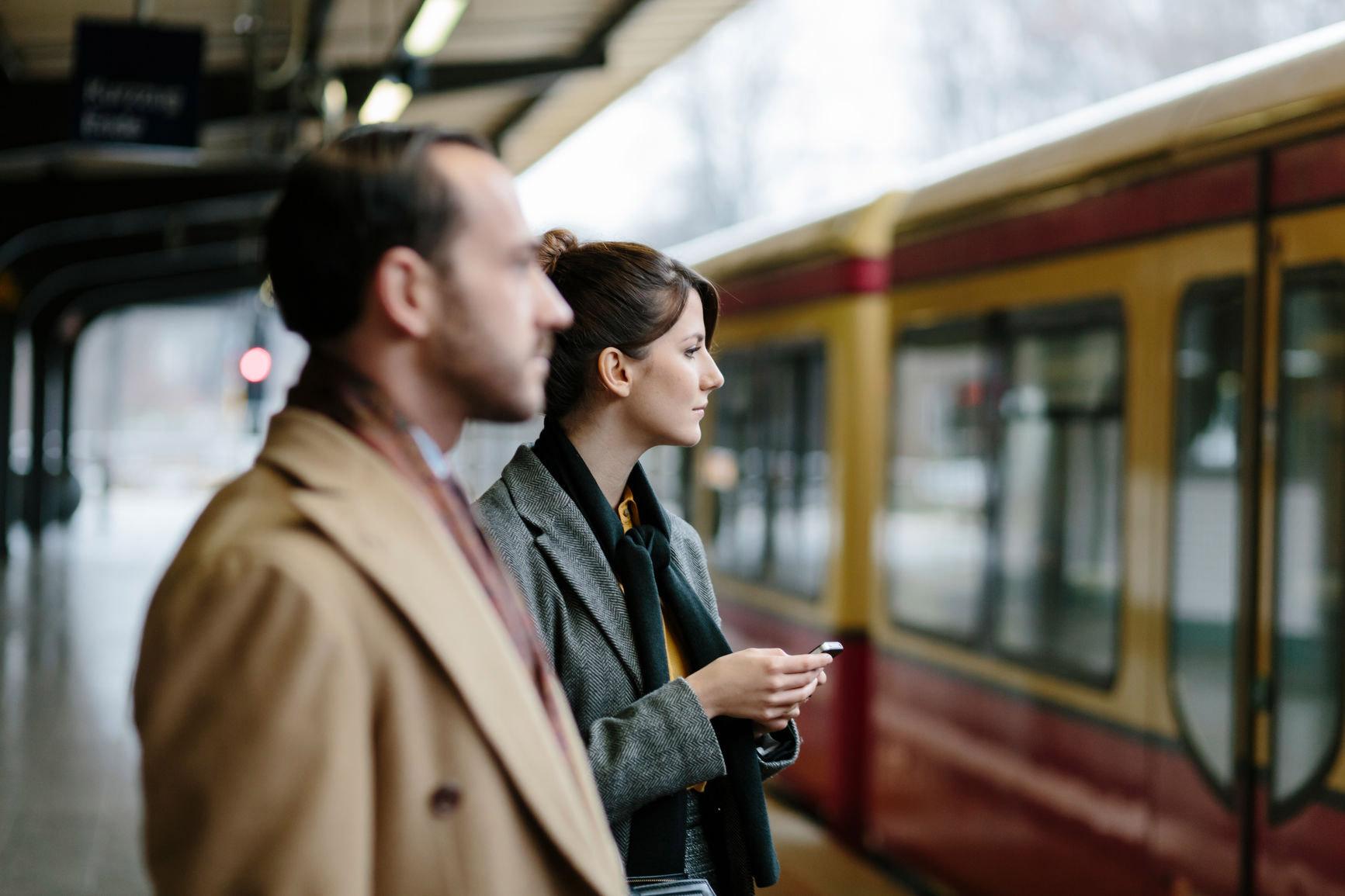 Fahrkosten: Zwei Menschen warten am Bahnsteig auf die einfahrende Bahn. 