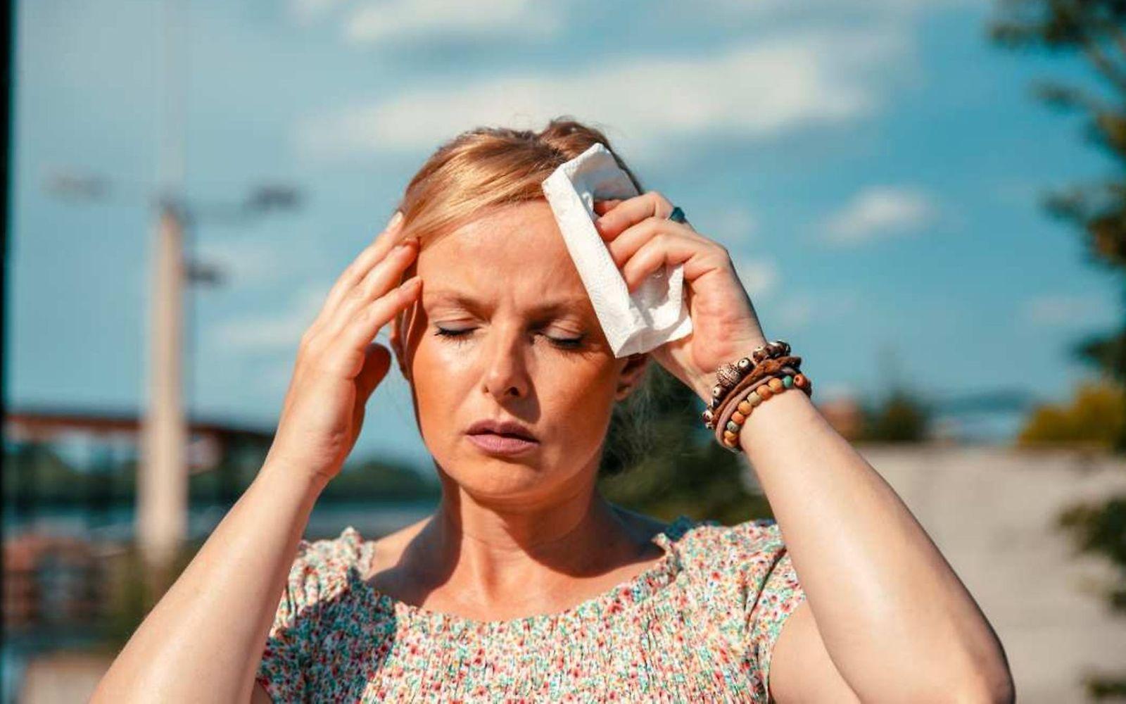 Symbolbild Hitzewelle: Eine Frau tupft sich die Schläfen ab