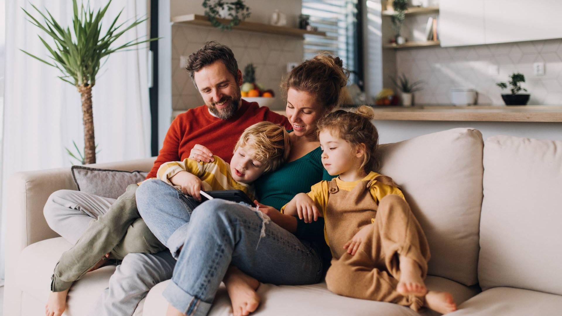 Familie sitzt auf Couch und guckt in ein Buch