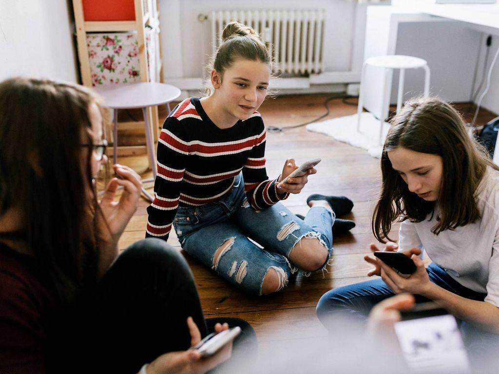 Medienkonsum bei Kindern: Mädchen sitzen mit Smartphones im Schlafzimmer