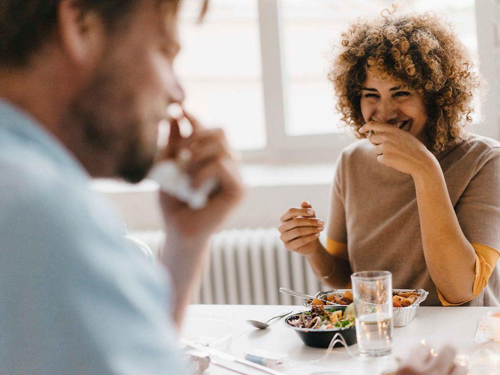 Bild: Kollegin und Kollege scherzen beim Mittagessen.