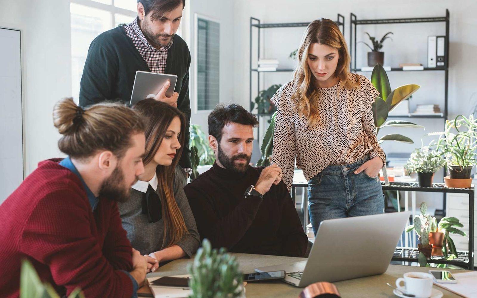 Symbolbild Insolvenzgeldumlage: Gruppe schaut auf Laptop.