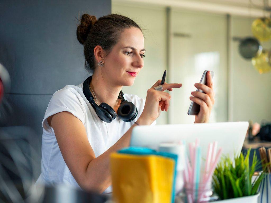 Bild: Junge Frau schaut auf ihr Handy und tippt auf den Screen.