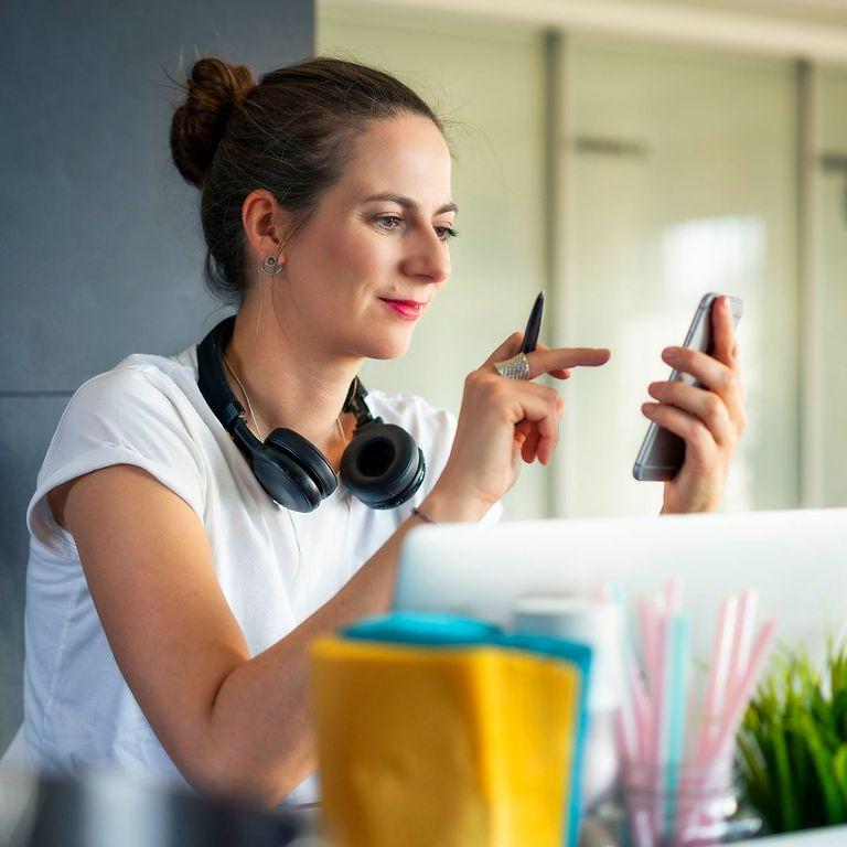 Bild: Junge Frau schaut auf ihr Handy und tippt auf den Screen.